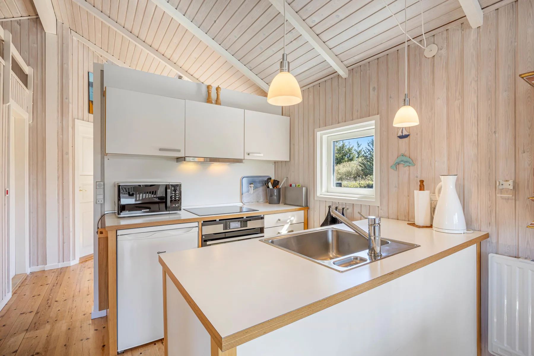 Una cocina luminosa con una isla central y paredes revestidas de madera clara.