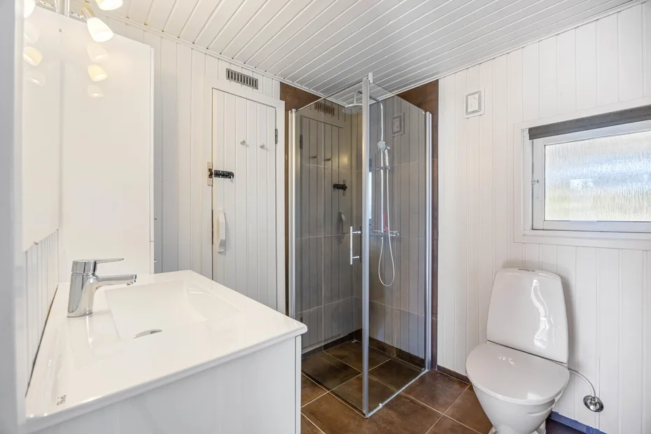 Un baño luminoso con lavabo, inodoro y ducha de vidrio.