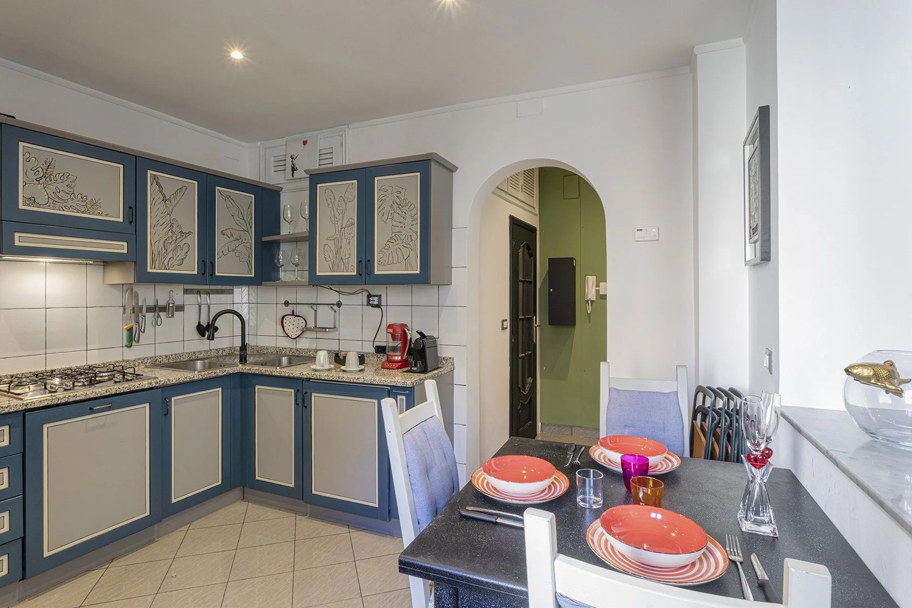Una cocina con gabinetes azules y una mesa de comedor puesta con platos.