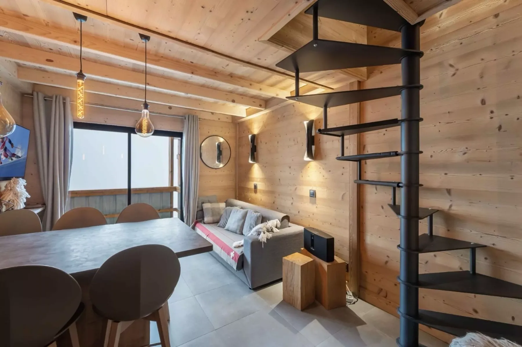 Una zona de estar y comedor revestida de madera, con sofá y mesa.
