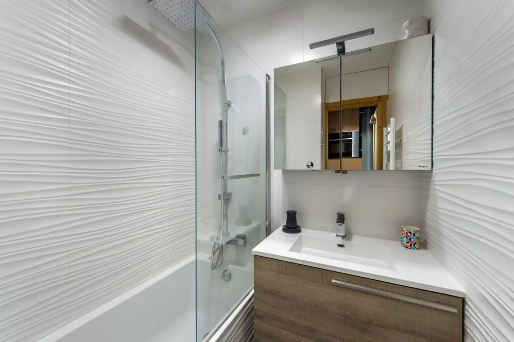 Un baño moderno con lavabo blanco y ducha de vidrio.