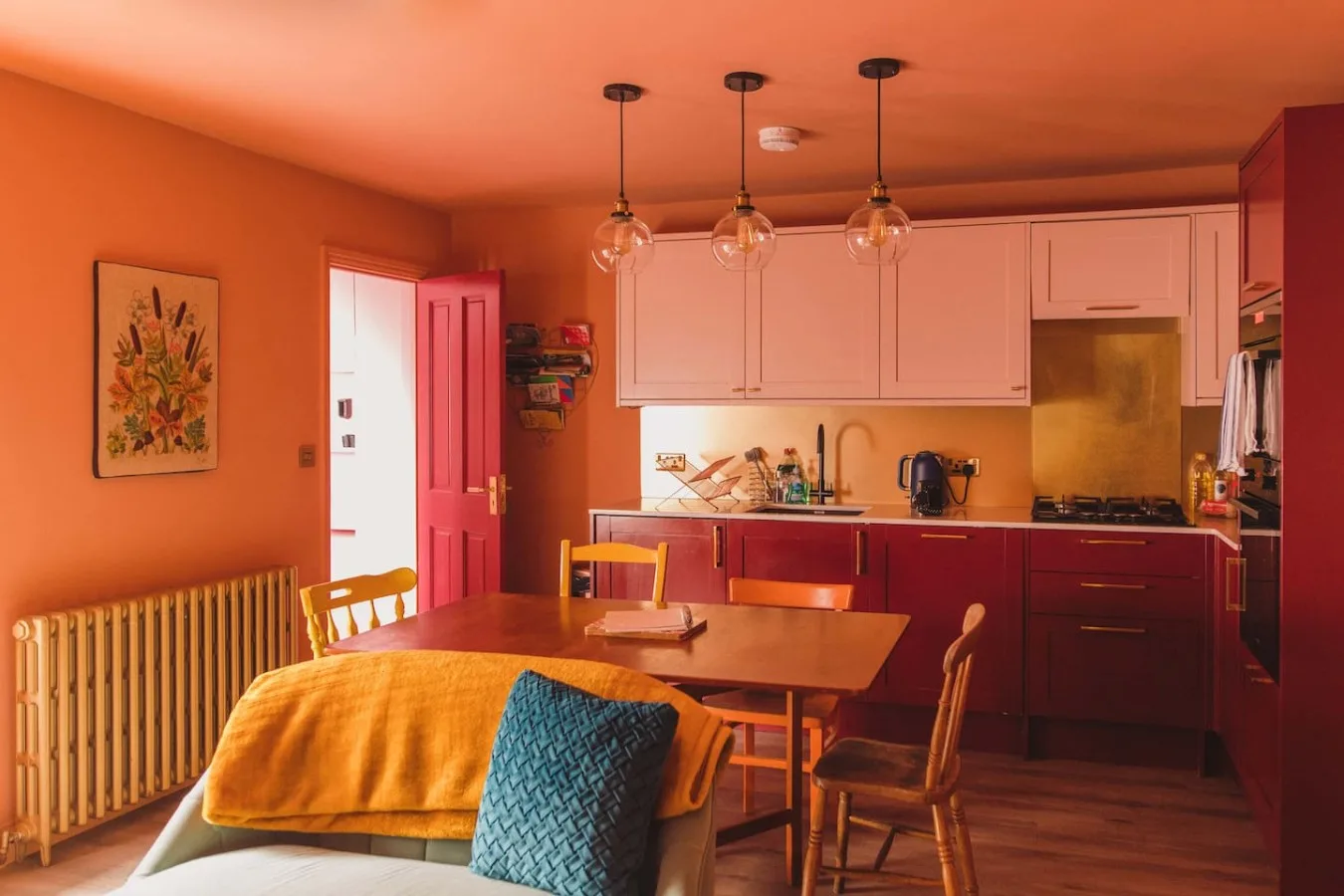 A warm-toned dining area with a wooden table beside the kitchen.