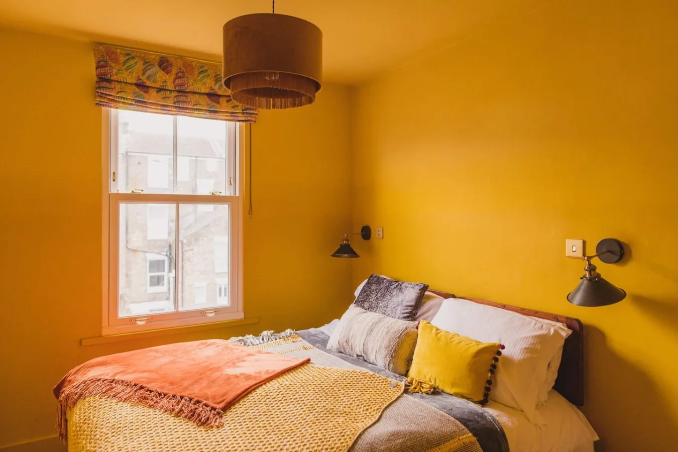A bedroom with a bed, patterned bedding, and a window.