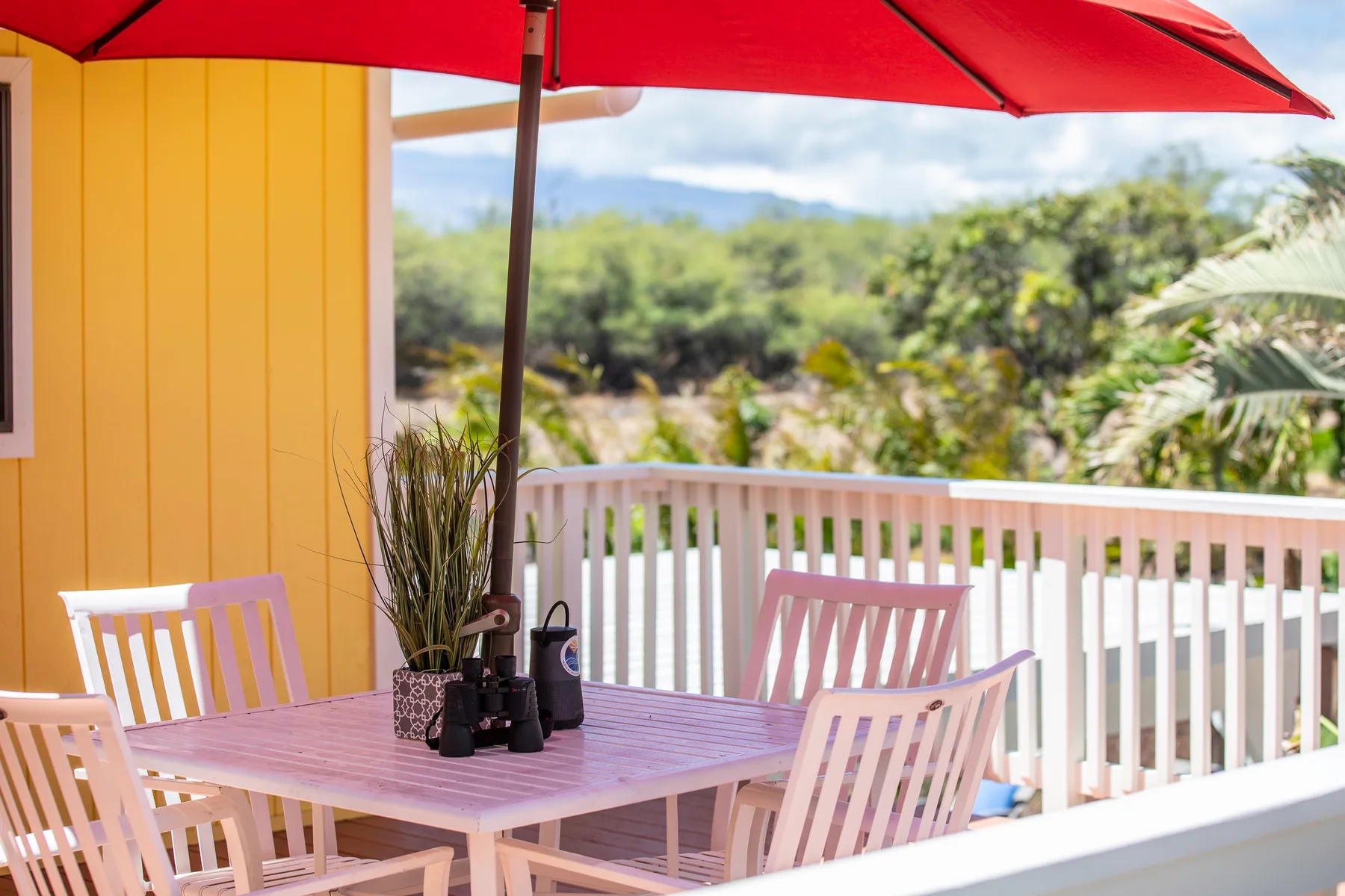 An outdoor patio with a table and seating under a red umbrella.