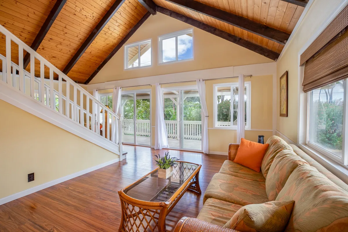 A bright living room with a seating area beneath a sloped wood ceiling.