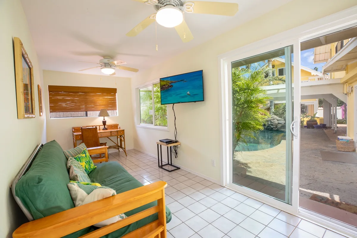 A bright living room with green seating and sliding glass doors opening to a patio.