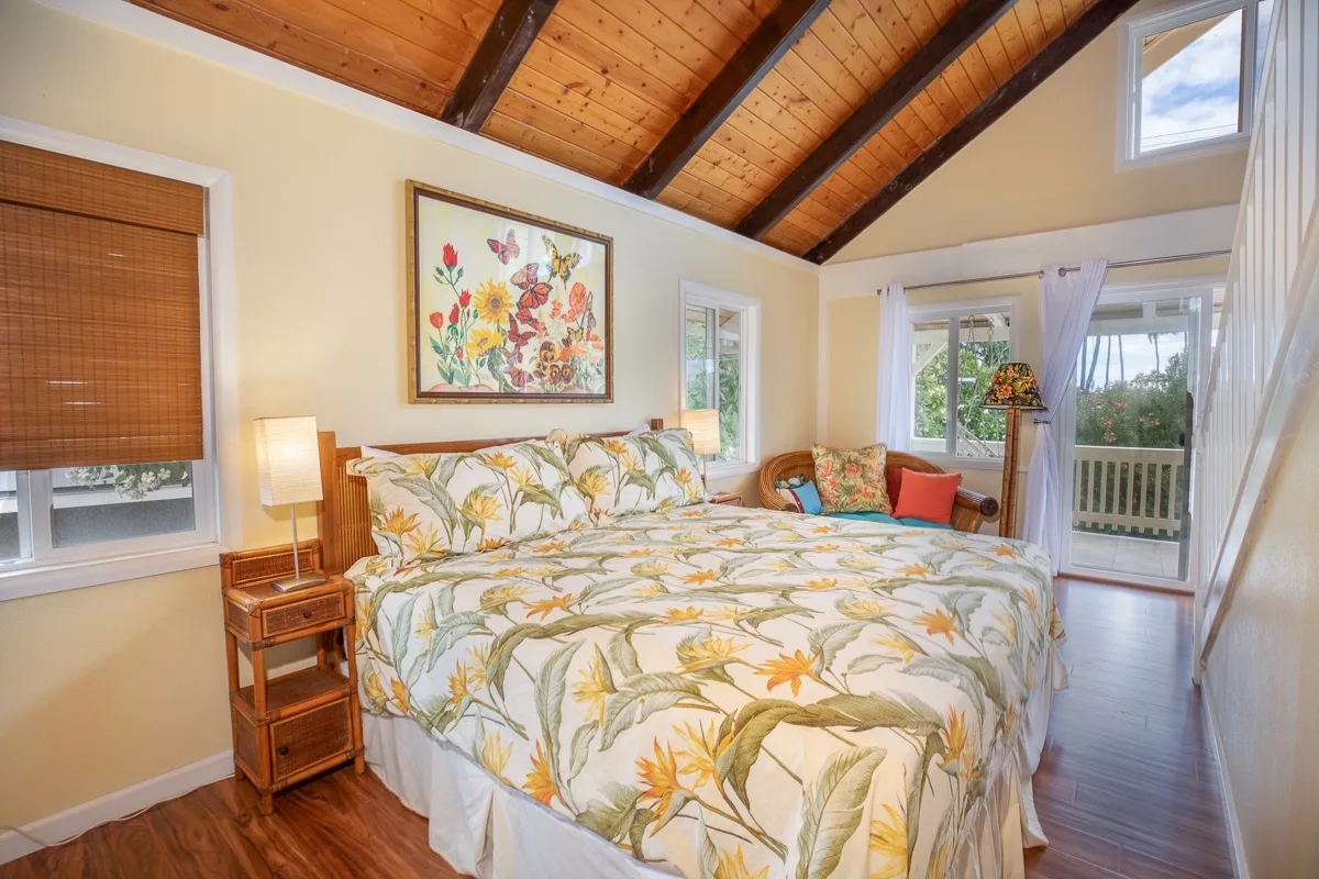 A bedroom with a floral bedspread and a sloped wooden ceiling.