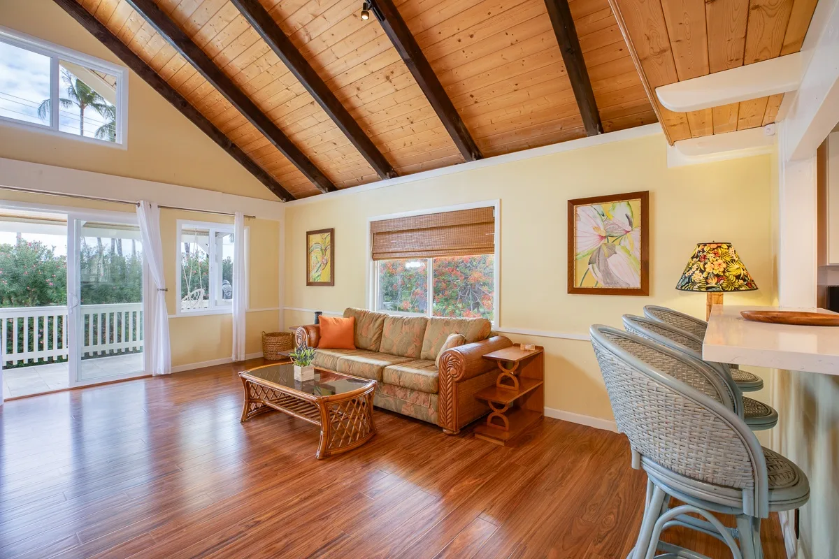 A bright living room has a seating area beneath a sloped wood ceiling.