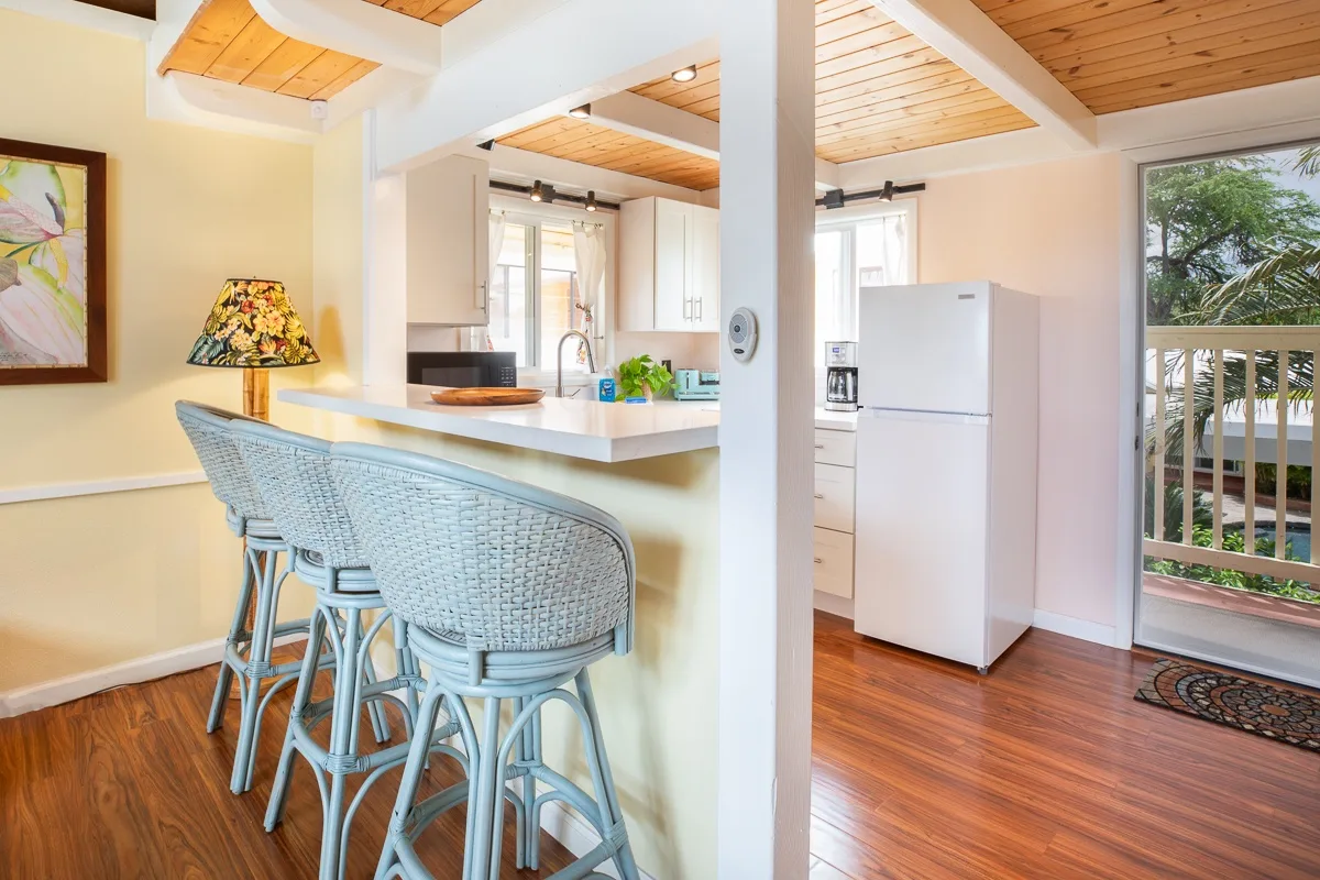 A kitchen with a raised counter and woven seating beneath a wood-paneled ceiling.