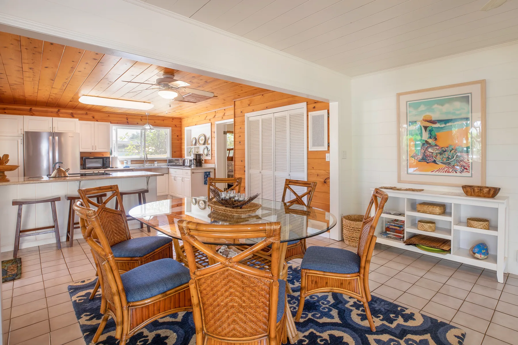 A dining area with wicker seating and a kitchen visible in the background.