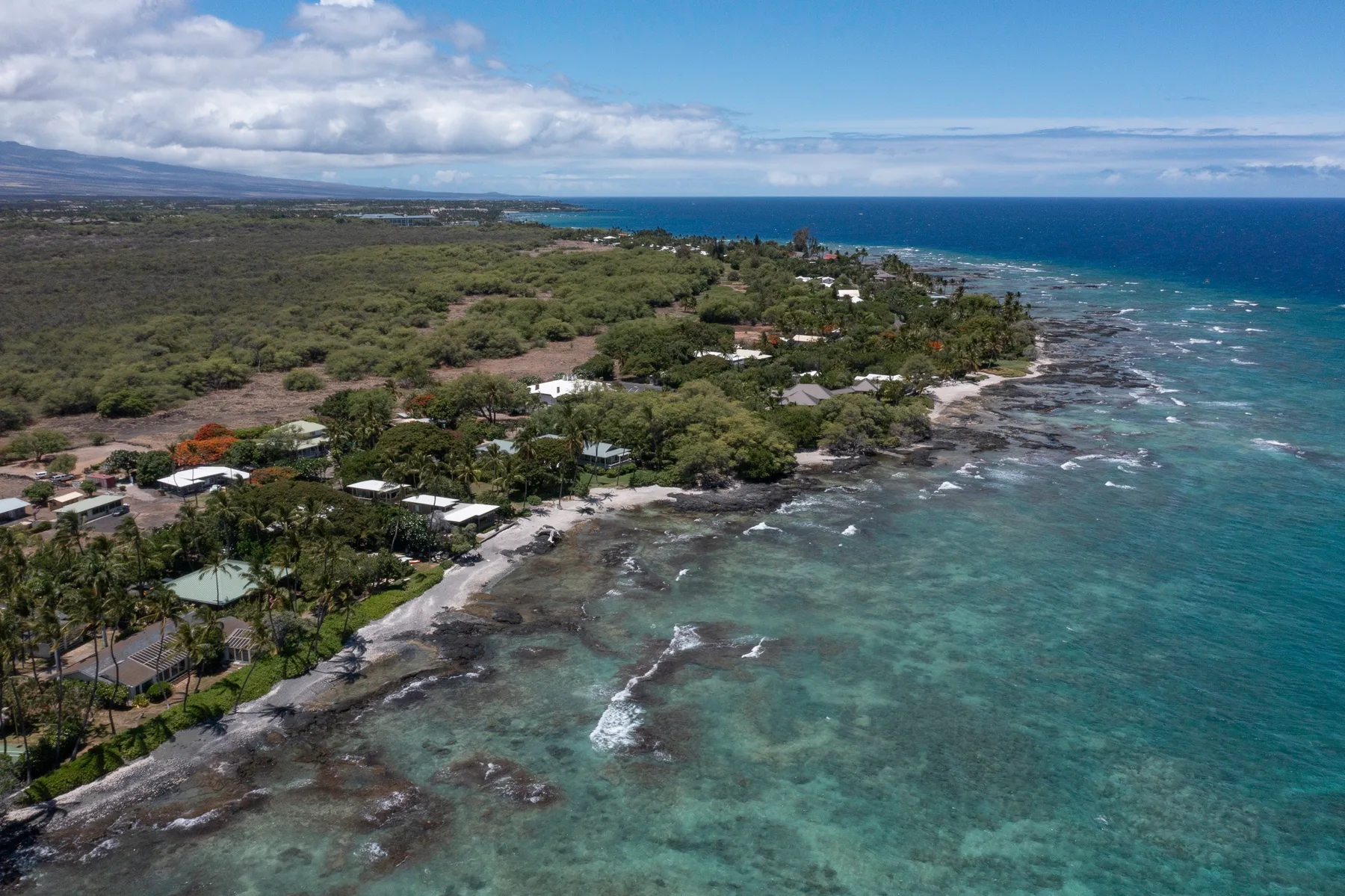 Aerial view of a tropical coastline with turquoise water and green vegetation.