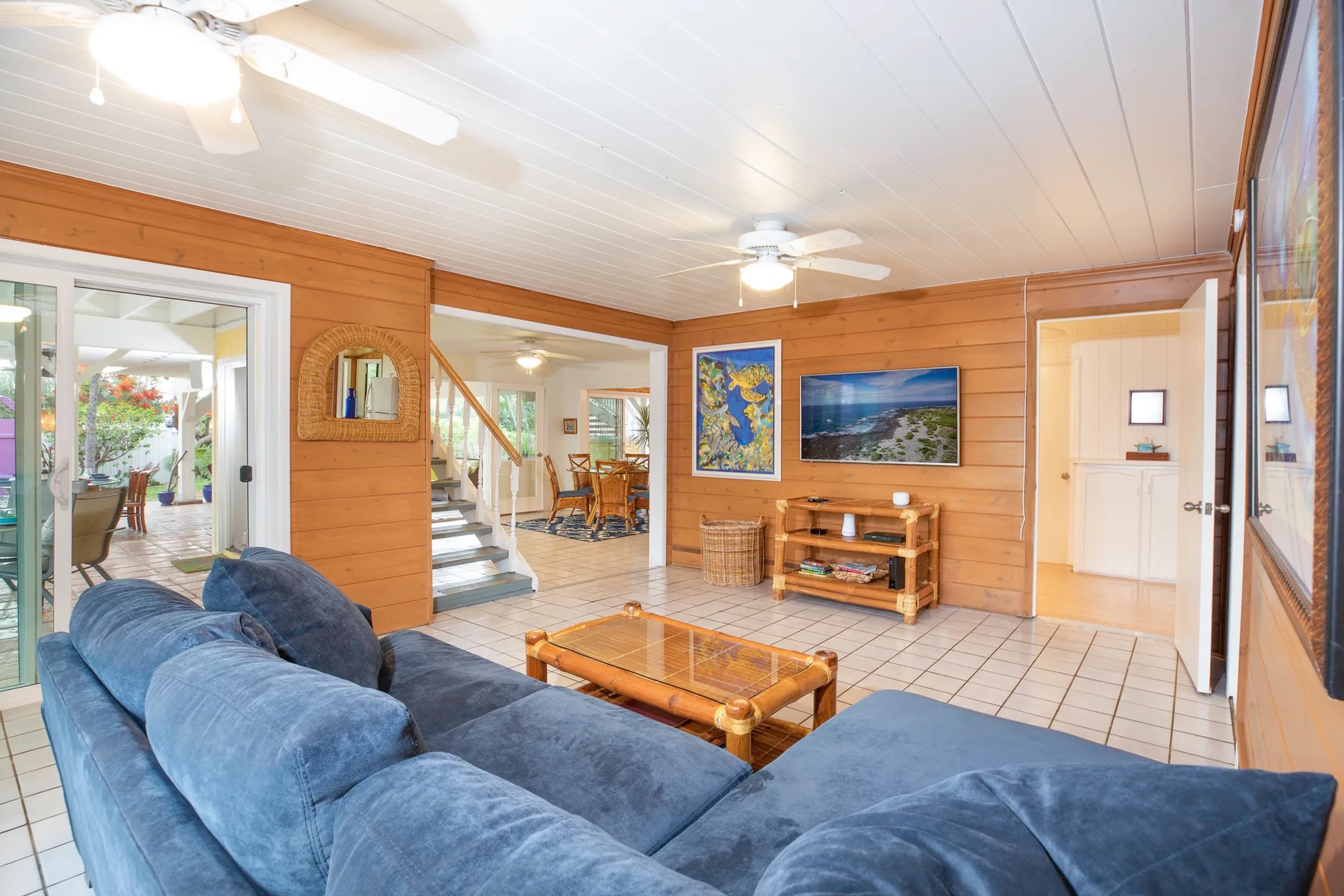 A wood-paneled living room with blue seating and a glass-topped coffee table.