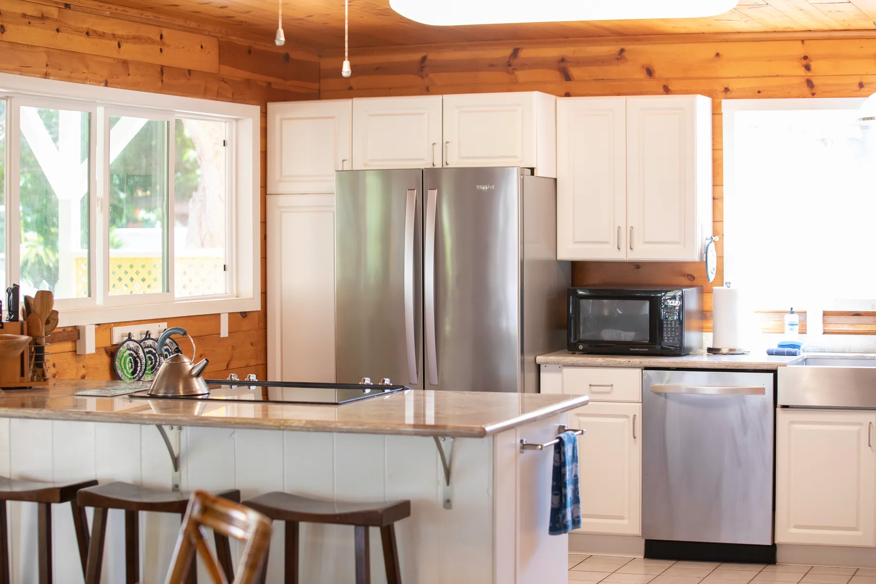 A kitchen with white cabinetry, stainless steel appliances, and a central island.