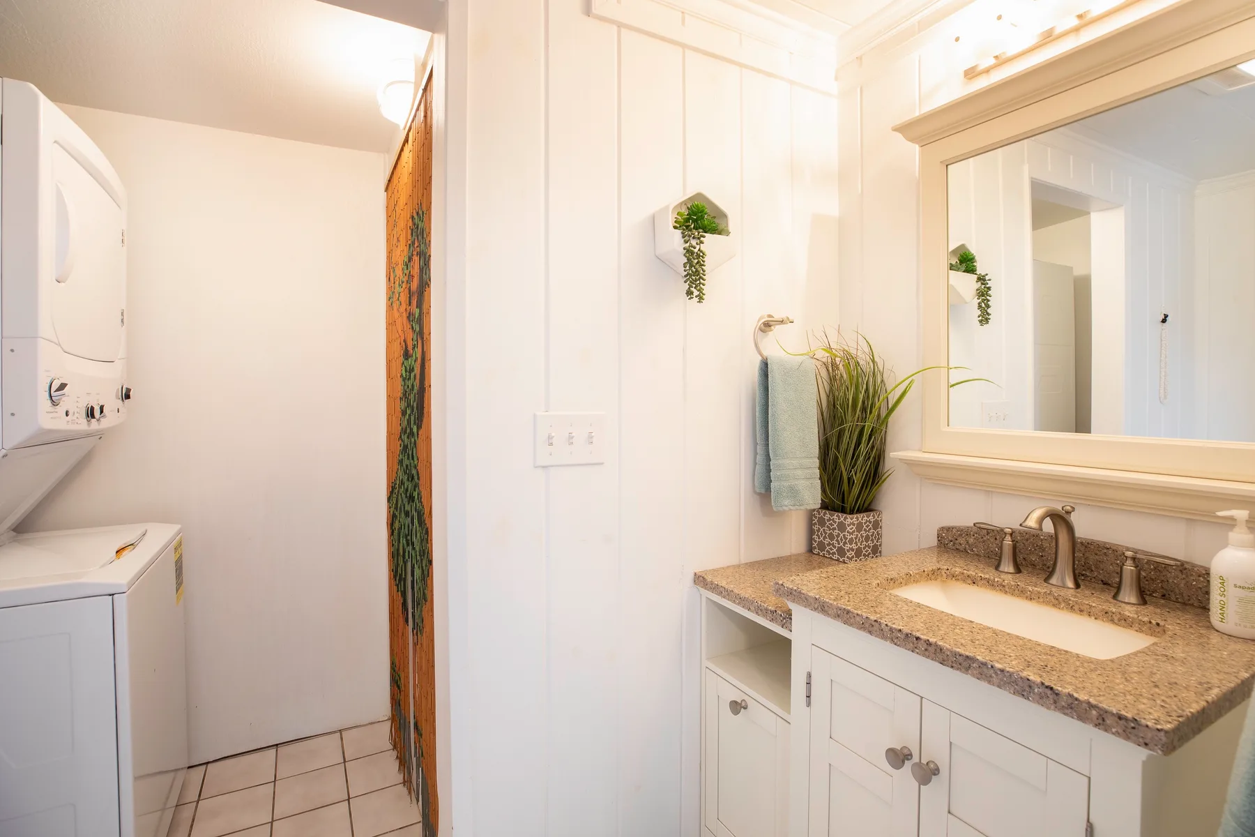 A bright bathroom with a sink vanity and laundry appliances.