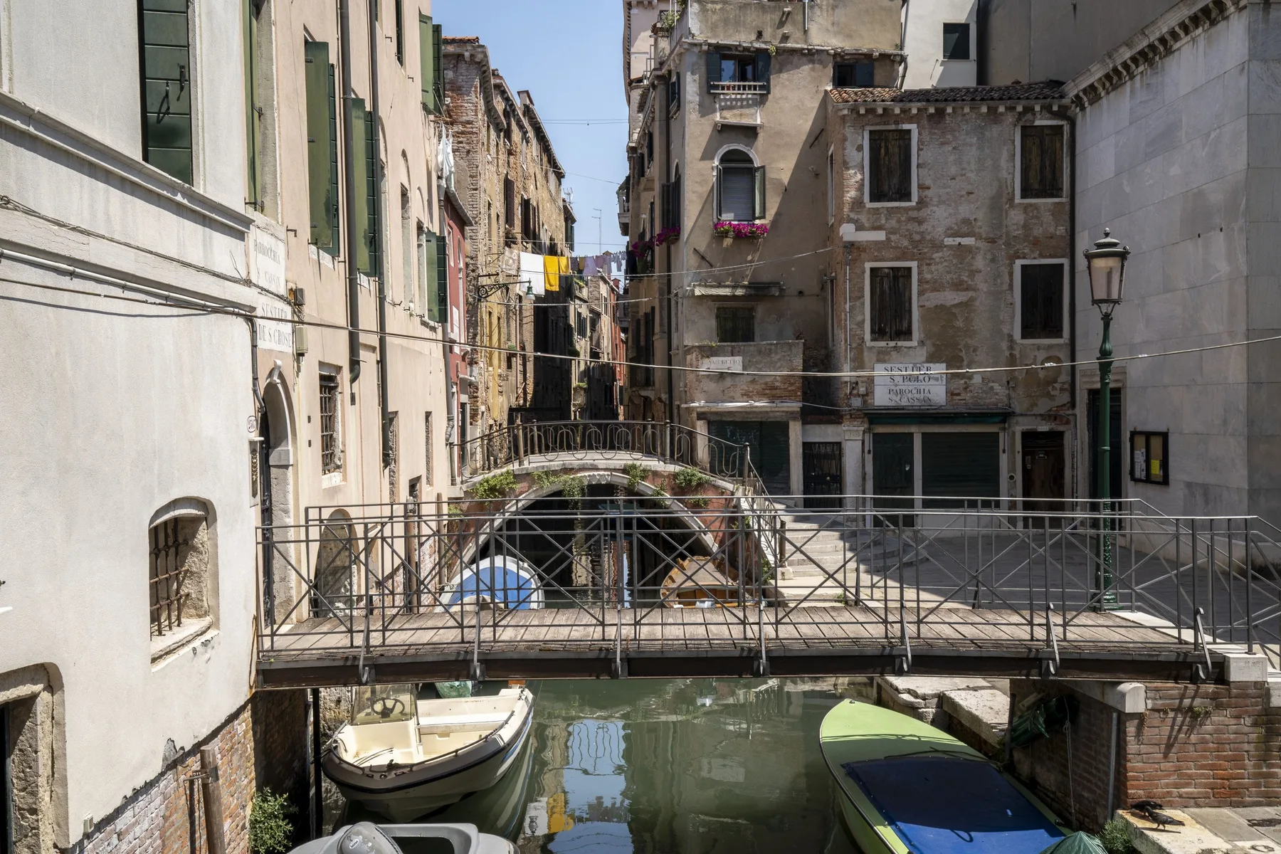 Un canal estrecho pasa bajo puentes peatonales entre edificios urbanos muy próximos.