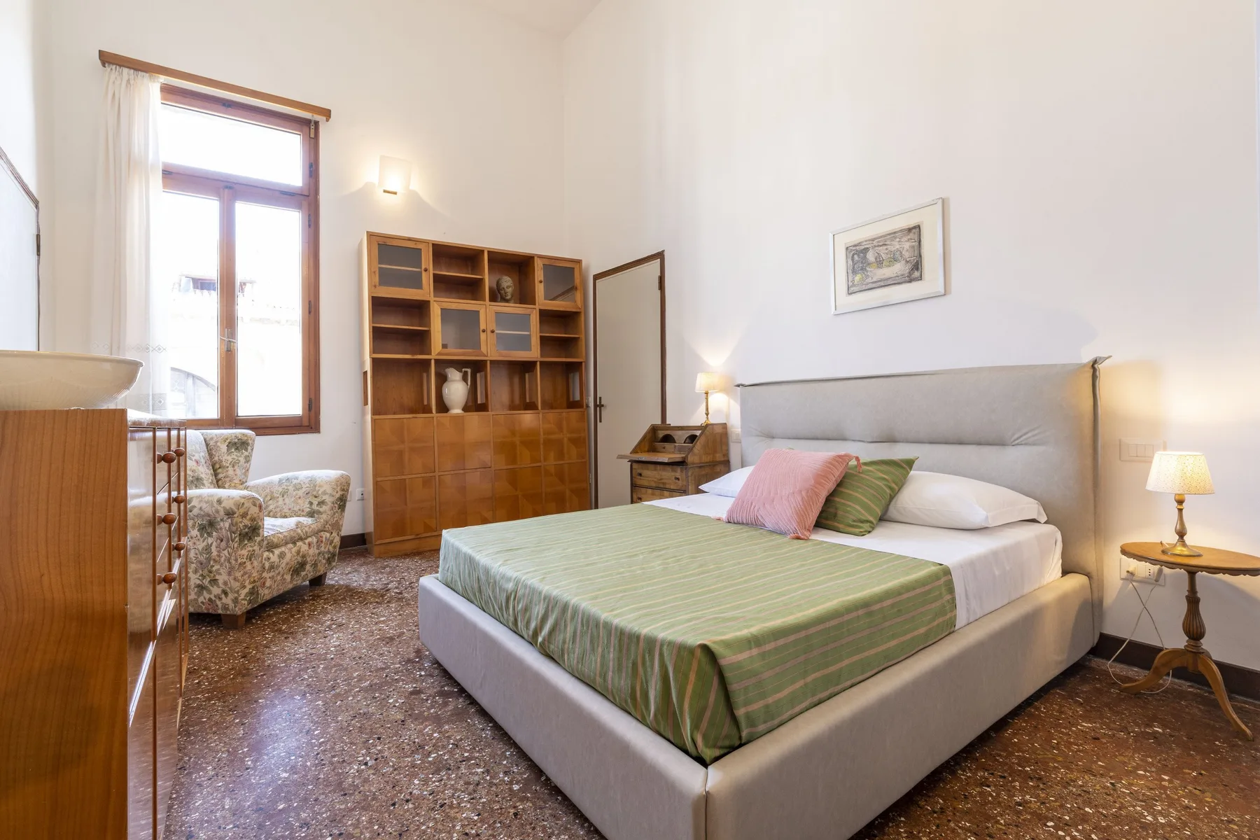 Un dormitorio con una cama grande, estanterías de madera y una ventana.