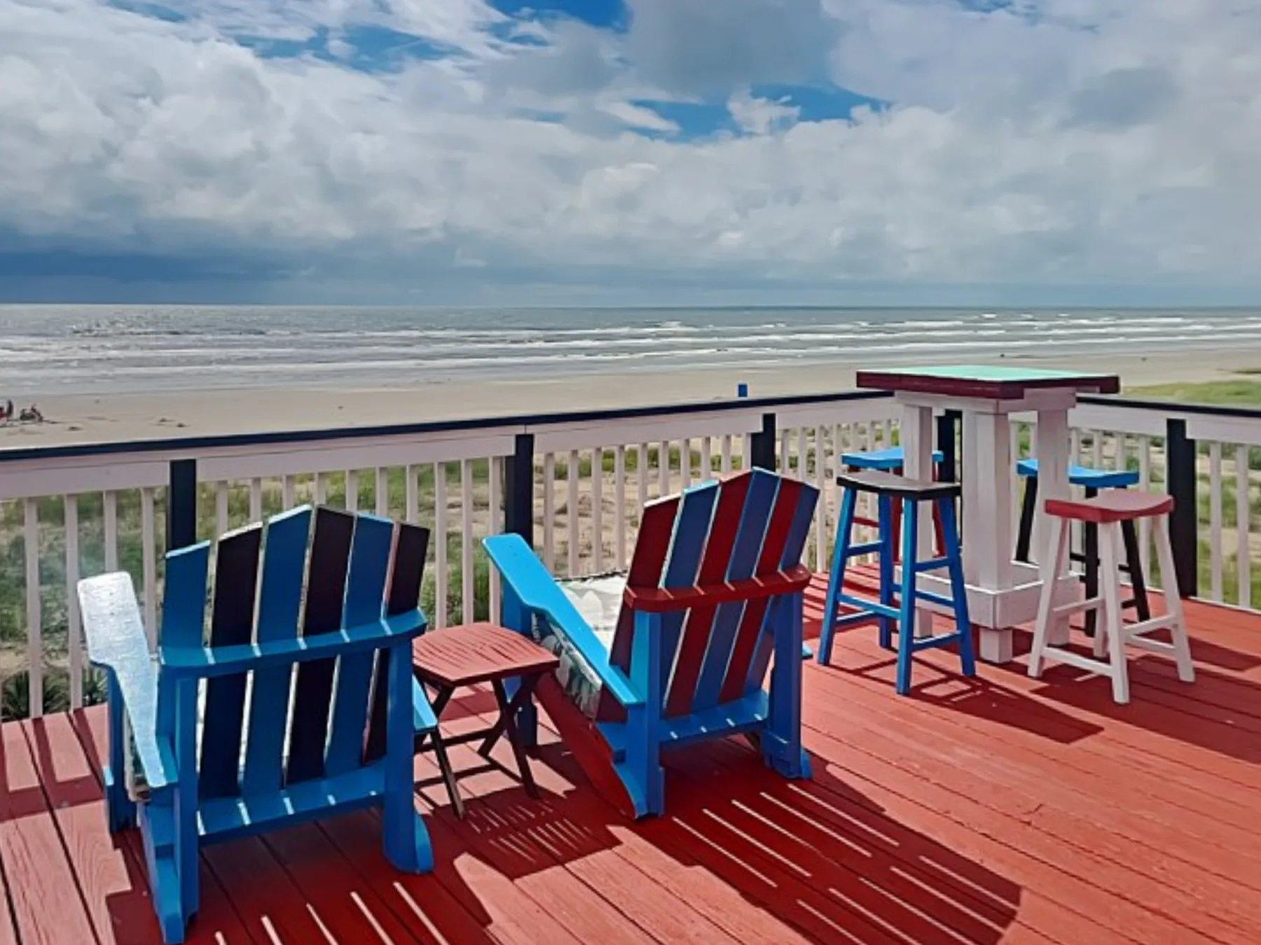 A beachfront deck with colorful seating overlooks the ocean.