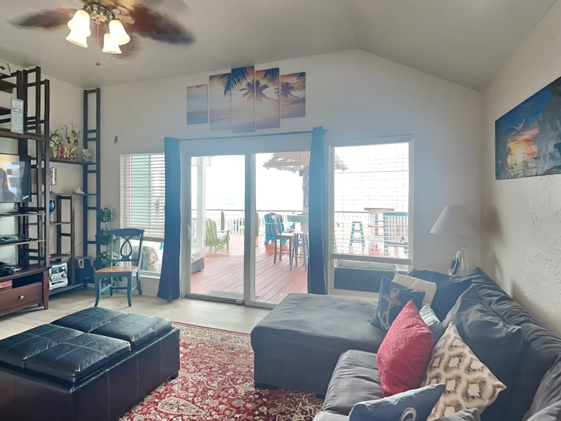 A living room with seating, a red rug, and glass doors opening onto a deck.