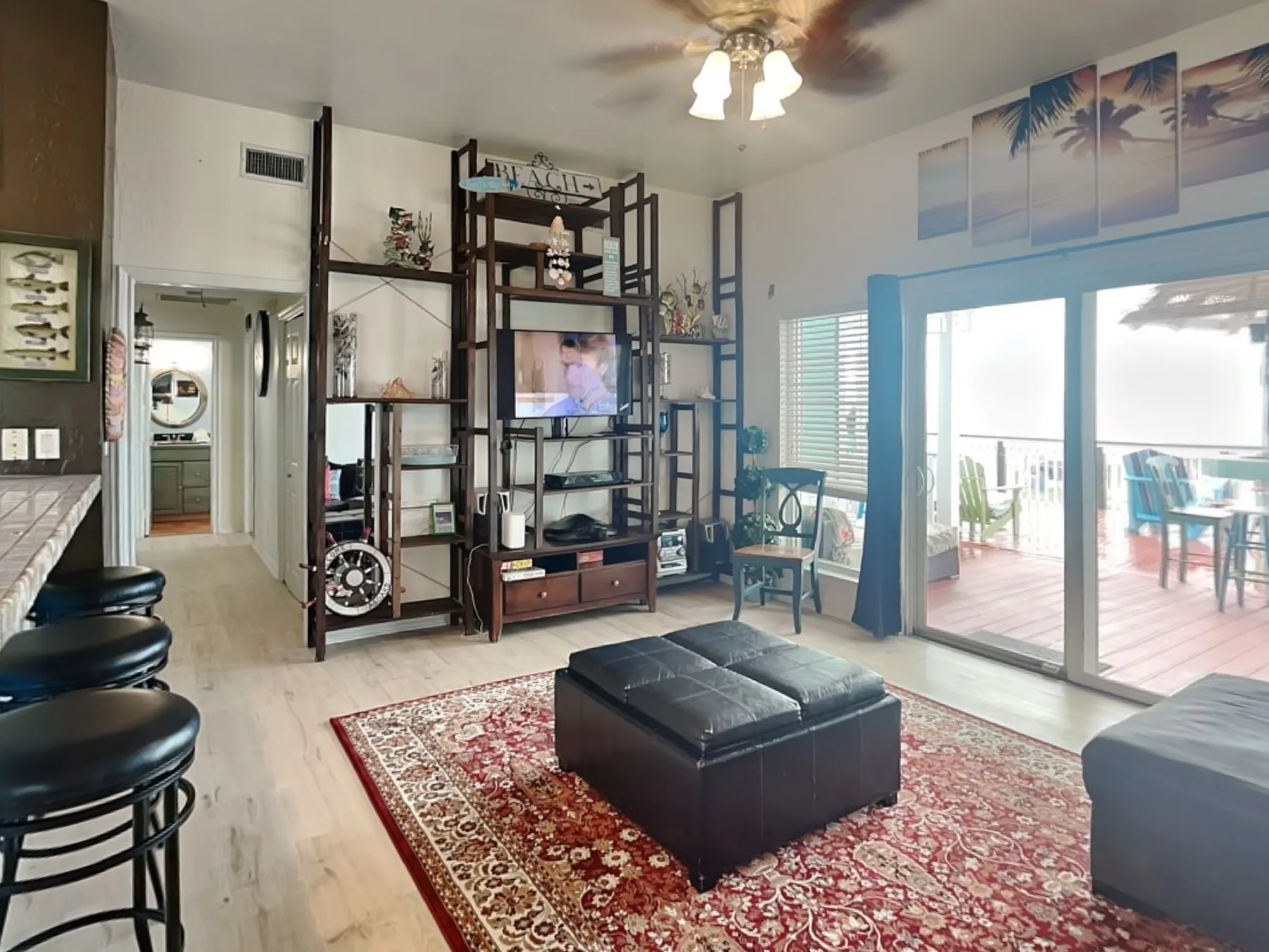 Una sala luminosa con televisor, asientos y puertas corredizas de vidrio que dan a un patio.