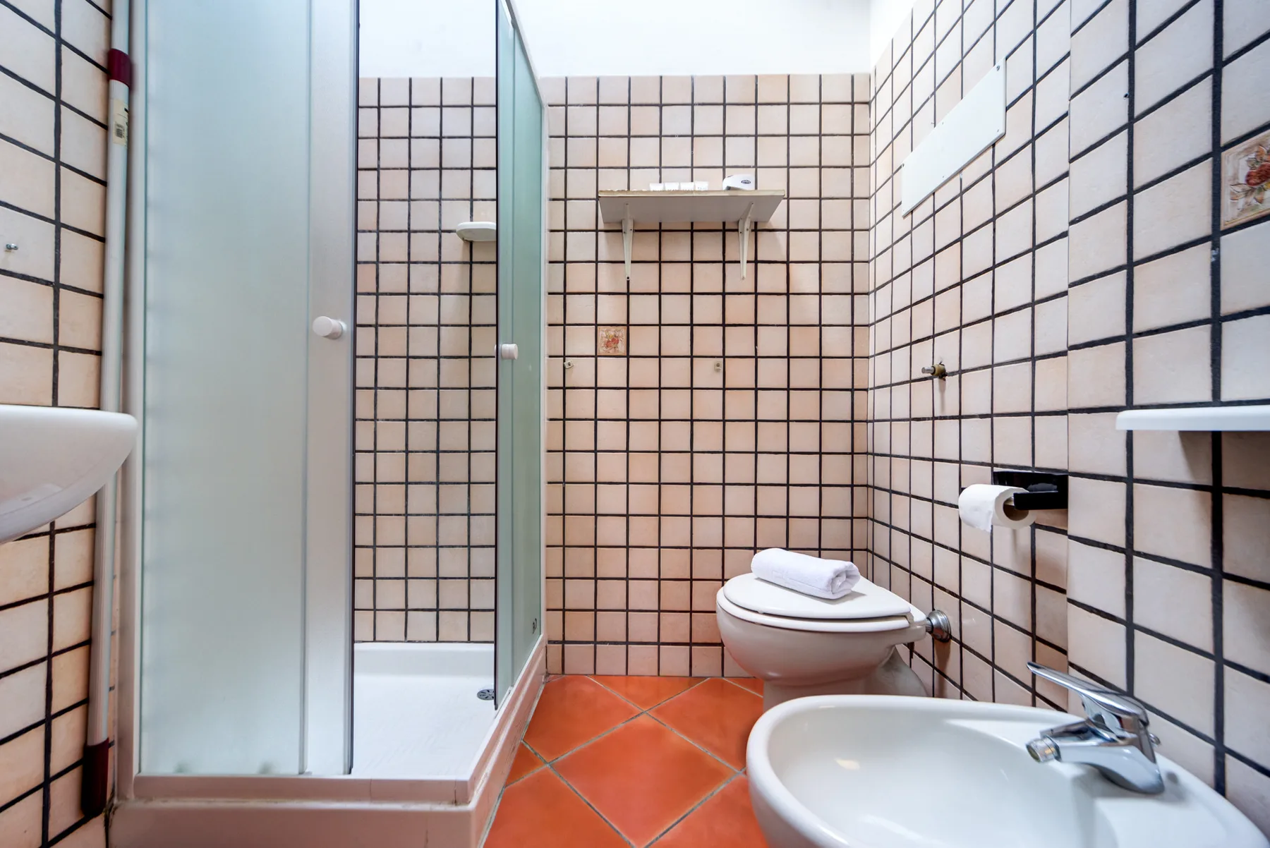 Un baño de azulejos con ducha, inodoro y lavabo.