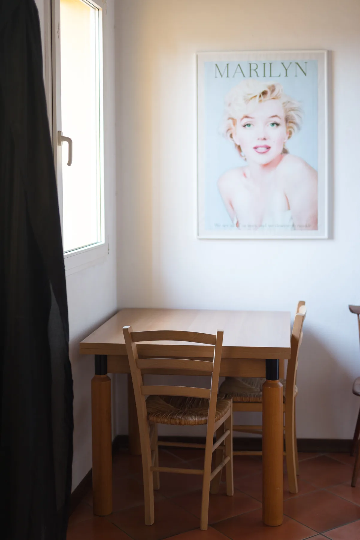 Un pequeño comedor con una mesa de madera y sillas junto a una ventana.