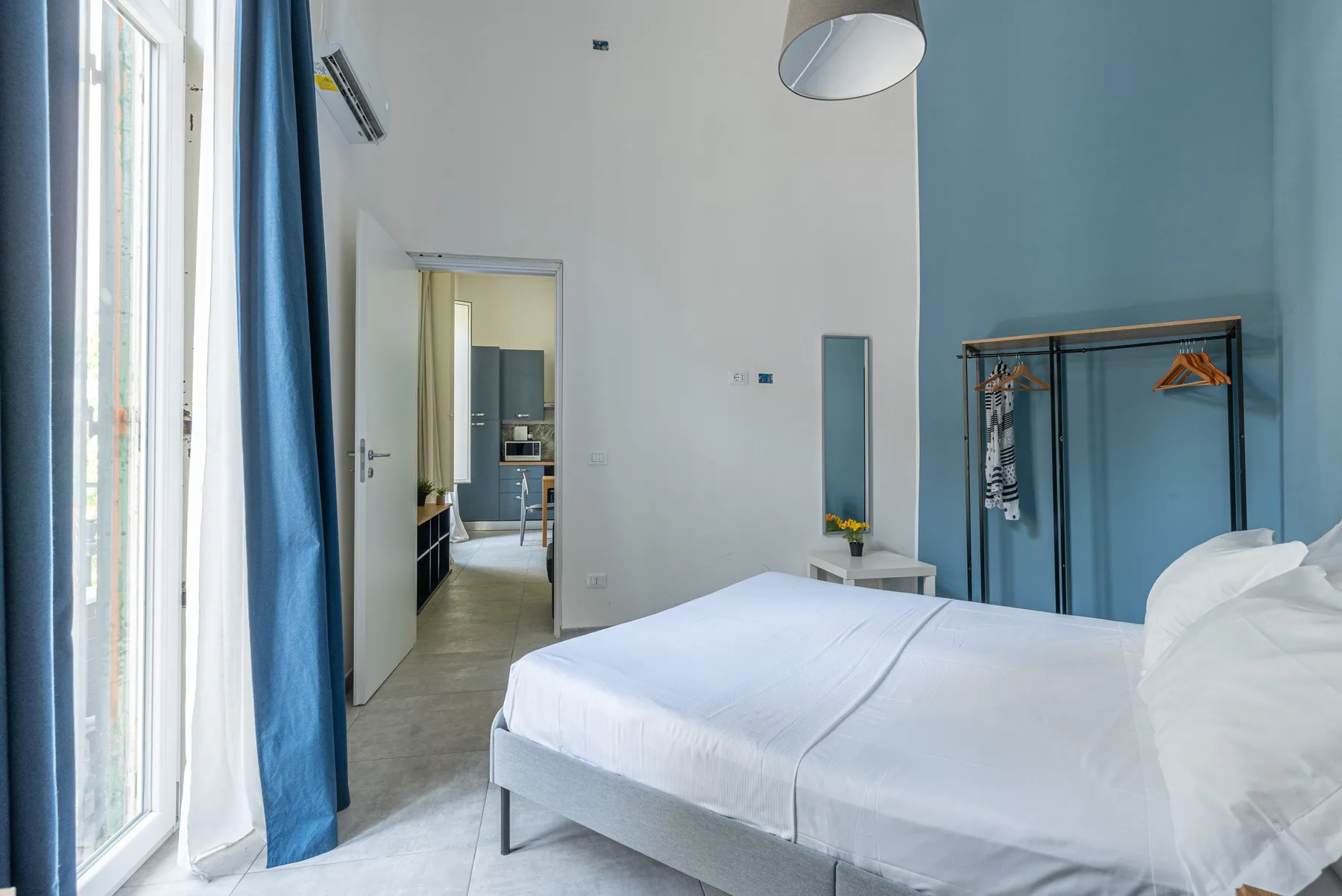Un dormitorio luminoso con una cama blanca y una puerta abierta.