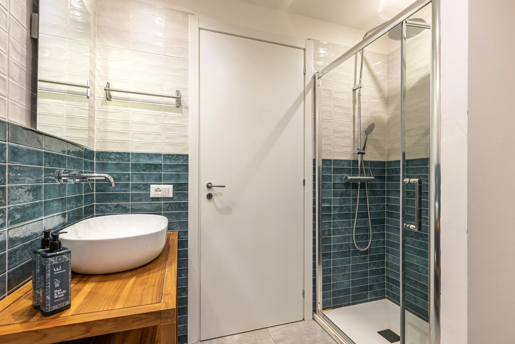A bathroom with a glass shower and a sink on a wooden vanity.