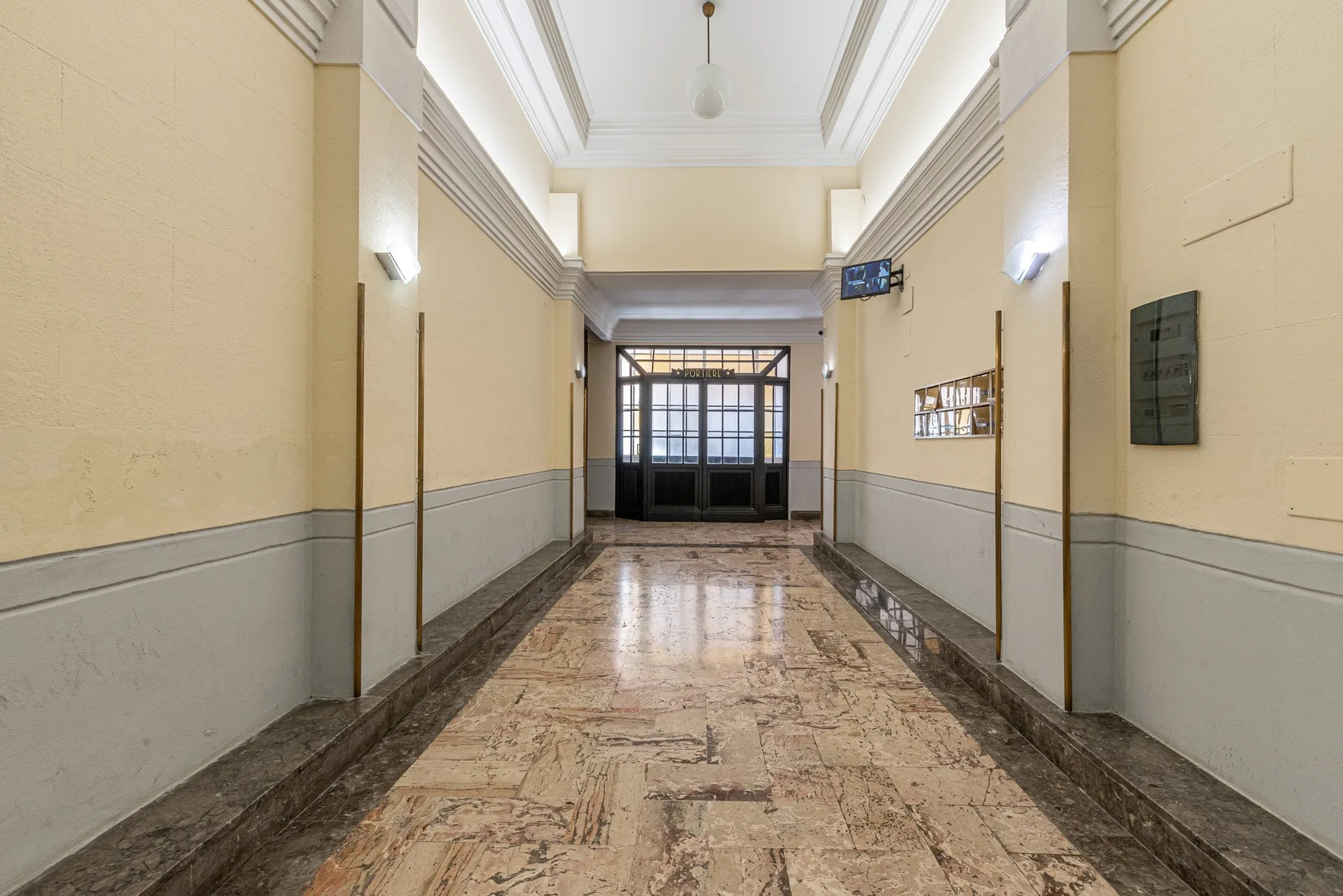 A long interior hallway leads to dark-framed glass doors, with a polished stone floor.
