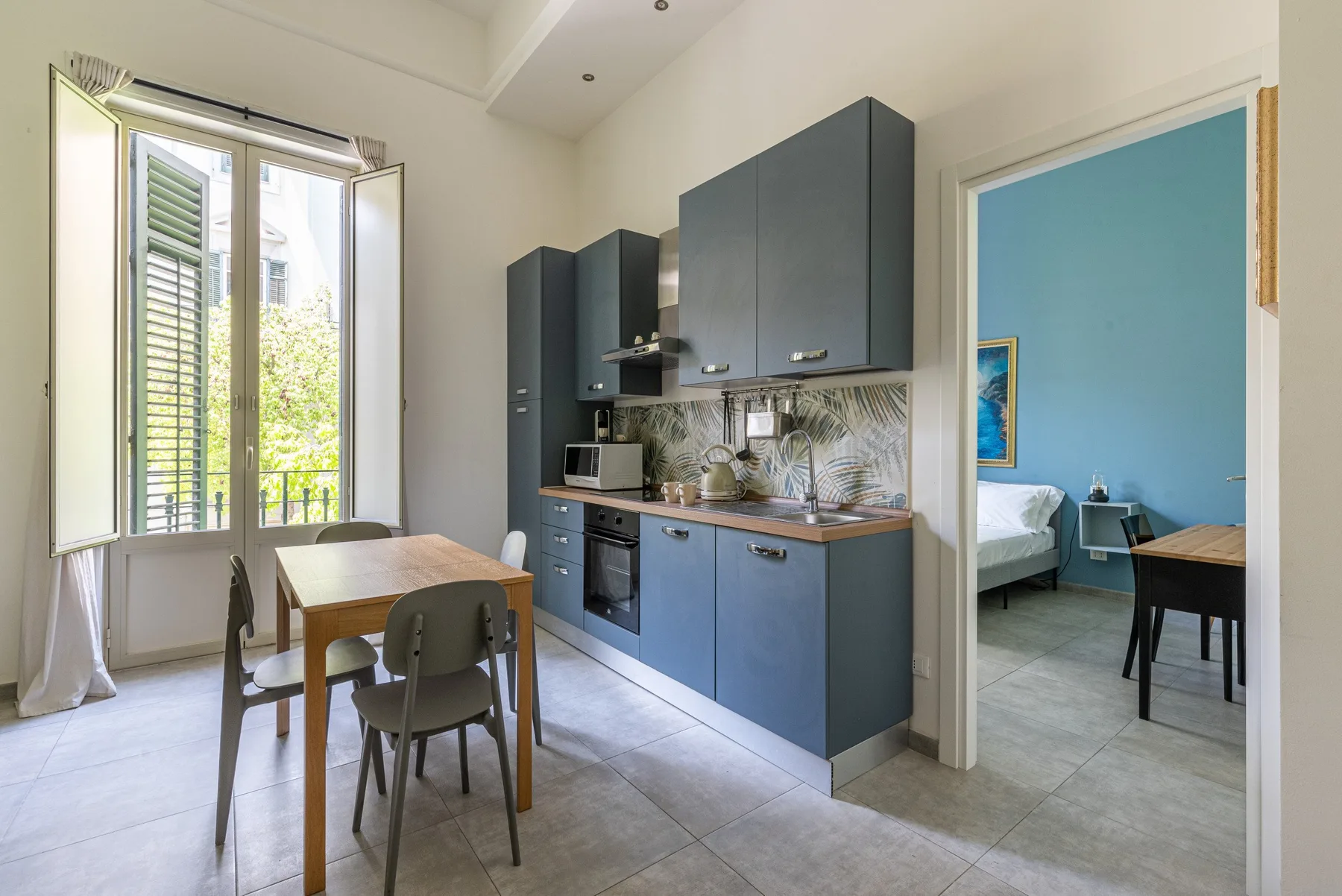 Una cocina compacta y comedor se abren a un dormitorio con paredes azules.