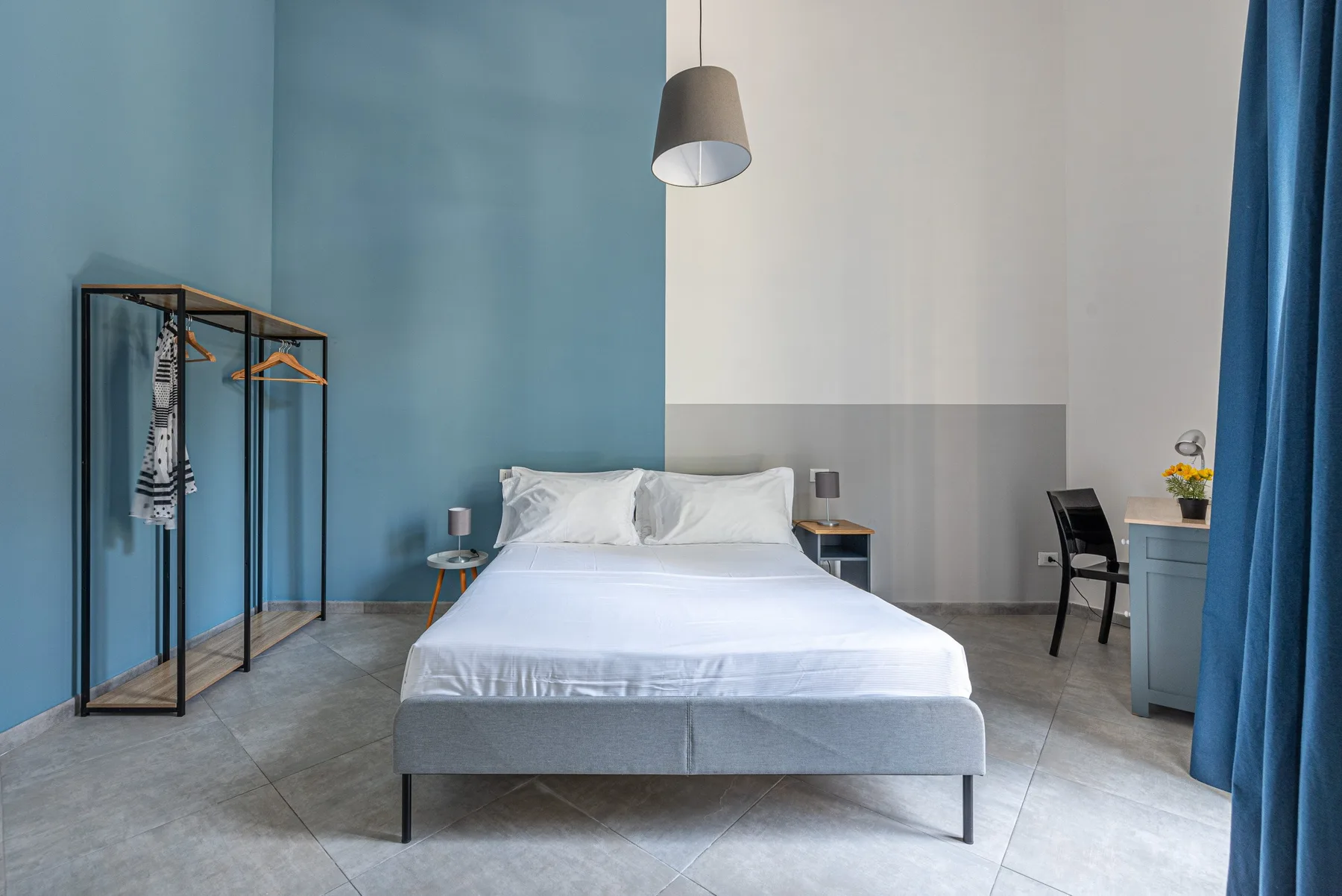Un dormitorio con una cama bien hecha y un perchero abierto.