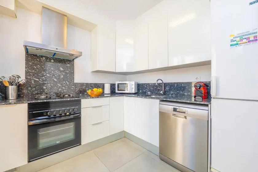 A bright kitchen with white cabinets, a dark countertop, and stainless steel appliances.