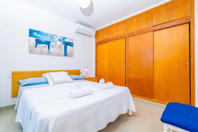 A bedroom with a neatly made bed and large wooden wardrobes.
