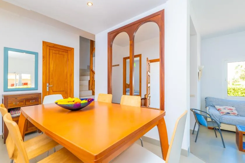 A dining area with a wooden table and chairs beside an arched doorway.