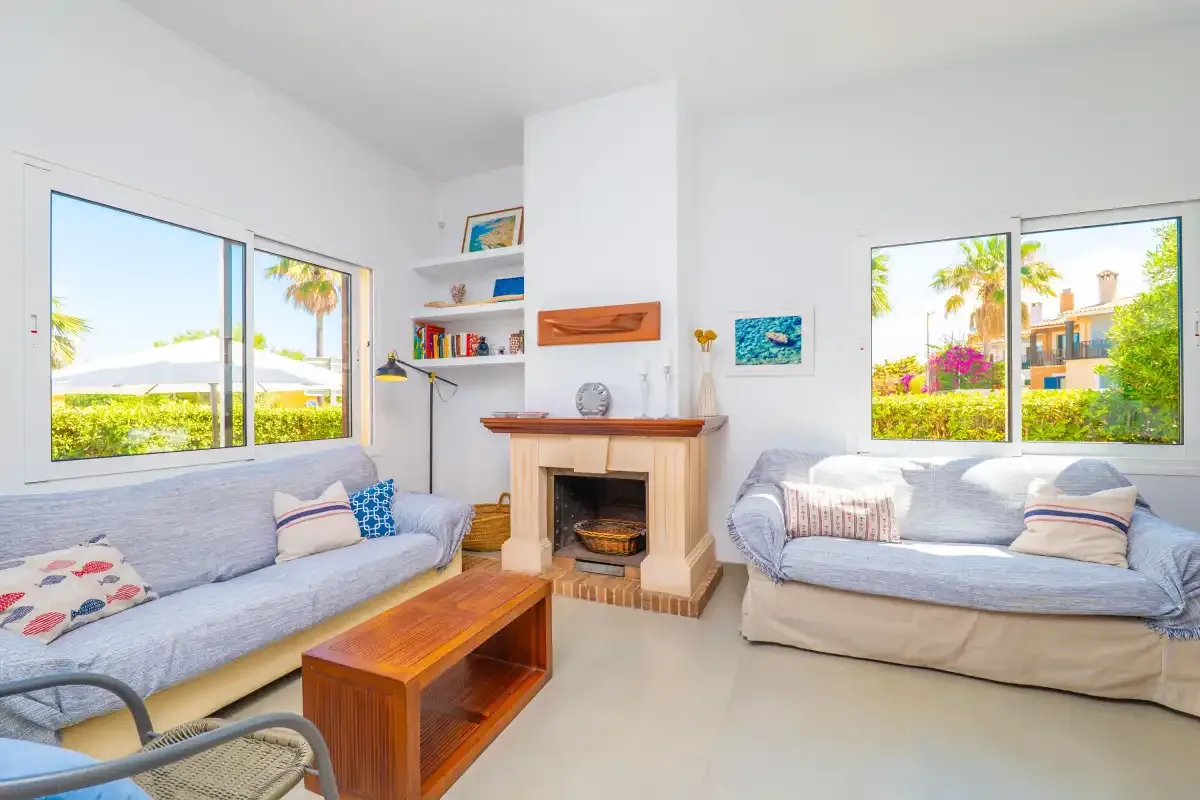 A bright living room with seating arranged around a central fireplace.