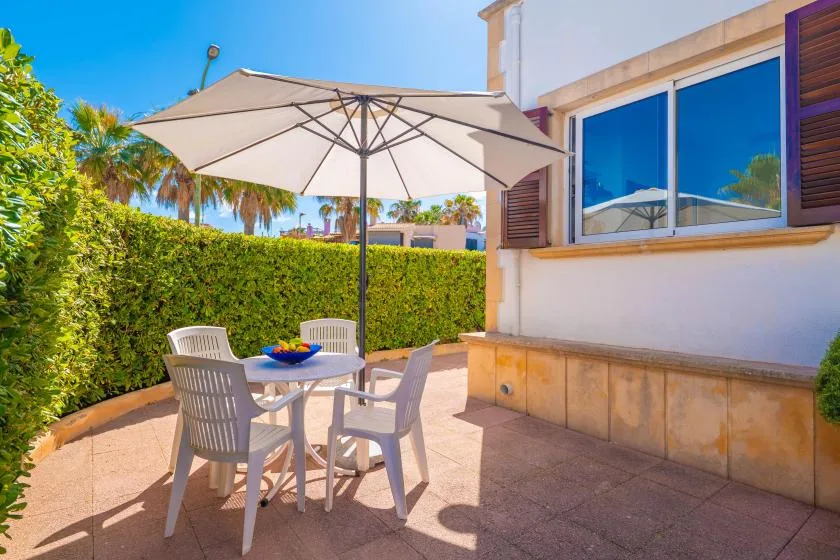 An outdoor patio with a table and seating beneath a large umbrella.