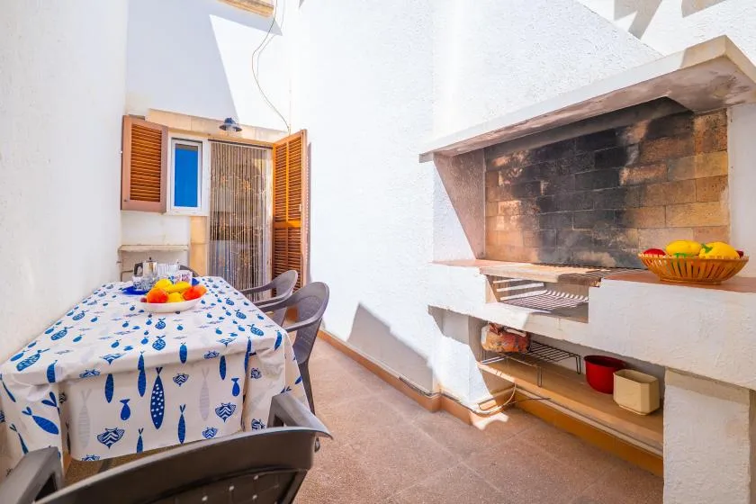 A dining area with a patterned table beside a built-in barbecue grill.
