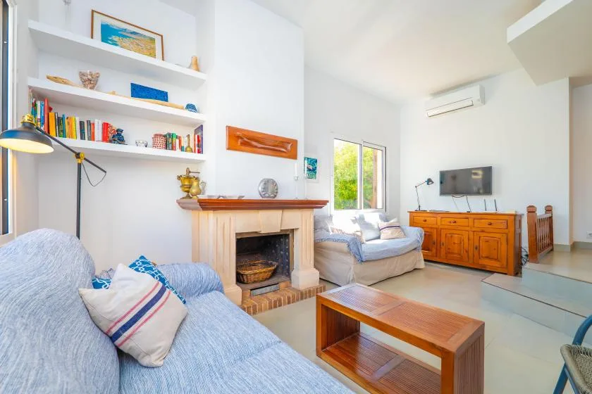 A bright living room with seating, a fireplace, and a wooden coffee table.