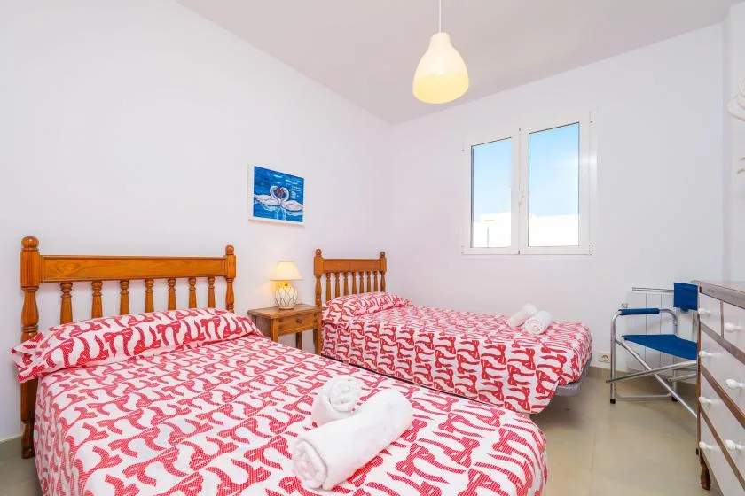 A bedroom with two beds covered in red-and-white patterned bedding.