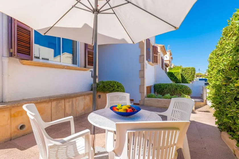 An outdoor patio with white seating beneath a large umbrella.