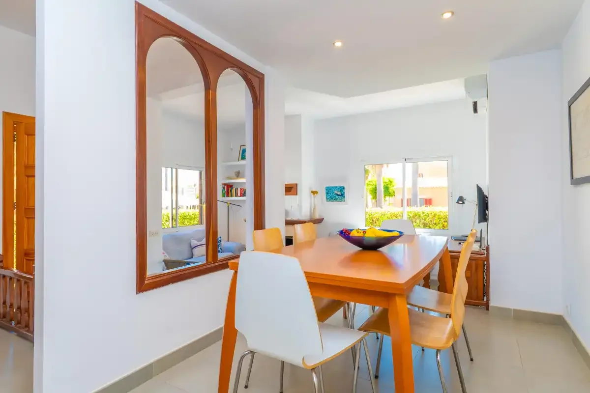 A bright dining area with a wooden table and chairs beside large windows.