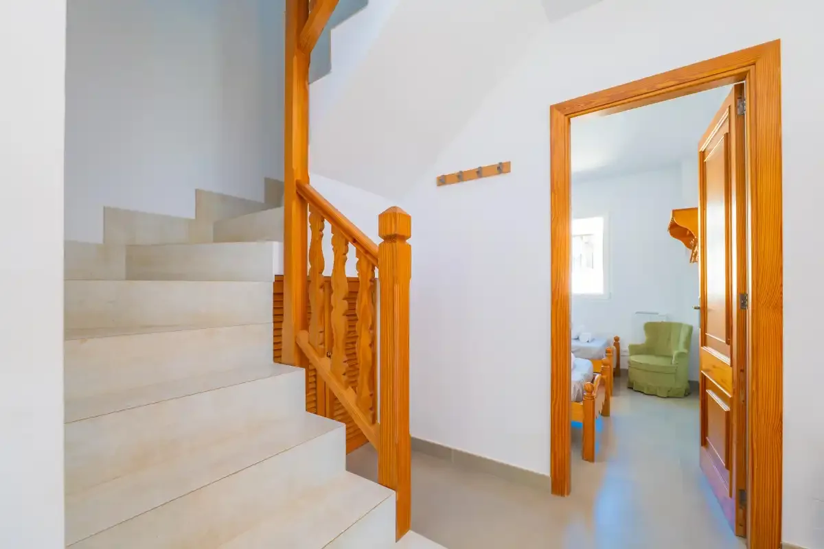 A bright interior hallway with a staircase and an open doorway.