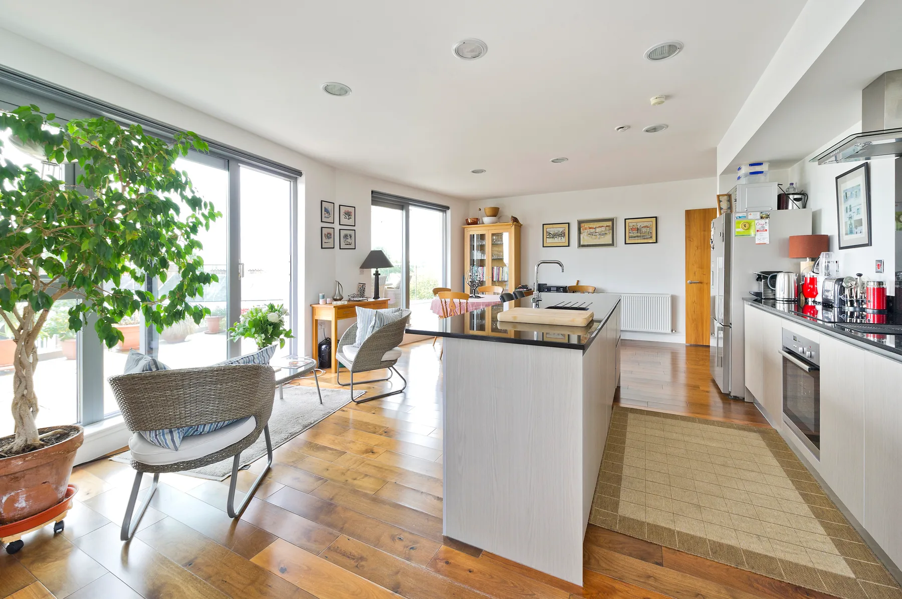 Una cocina y comedor luminosos con una isla central y grandes ventanales.