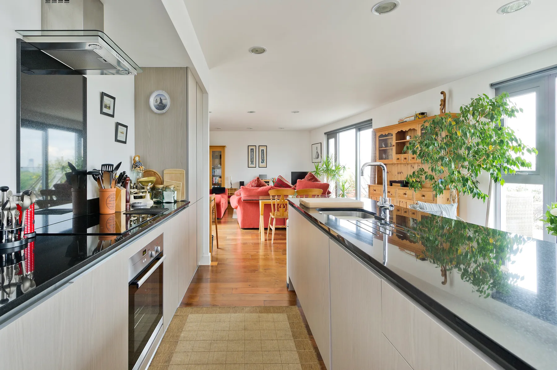 Una cocina luminosa se abre a una sala de estar, con amplias encimeras y ventanas grandes.