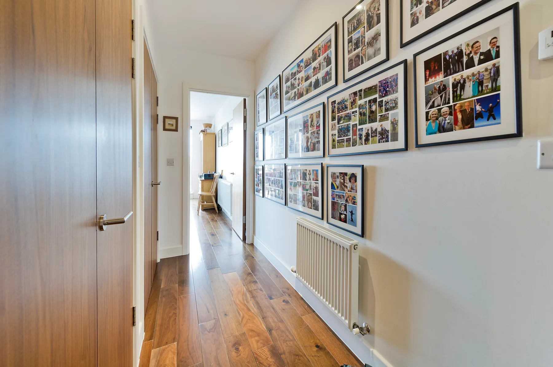 Un pasillo con fotografías enmarcadas en la pared, sobre un radiador.