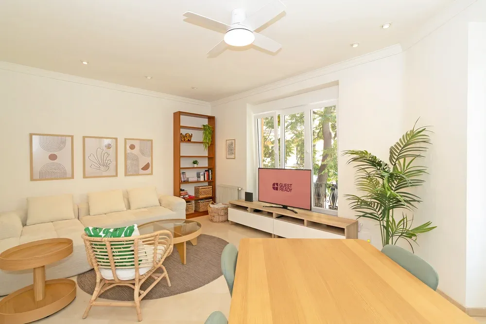 Una luminosa sala de estar con asientos, un televisor y una mesa de comedor de madera.