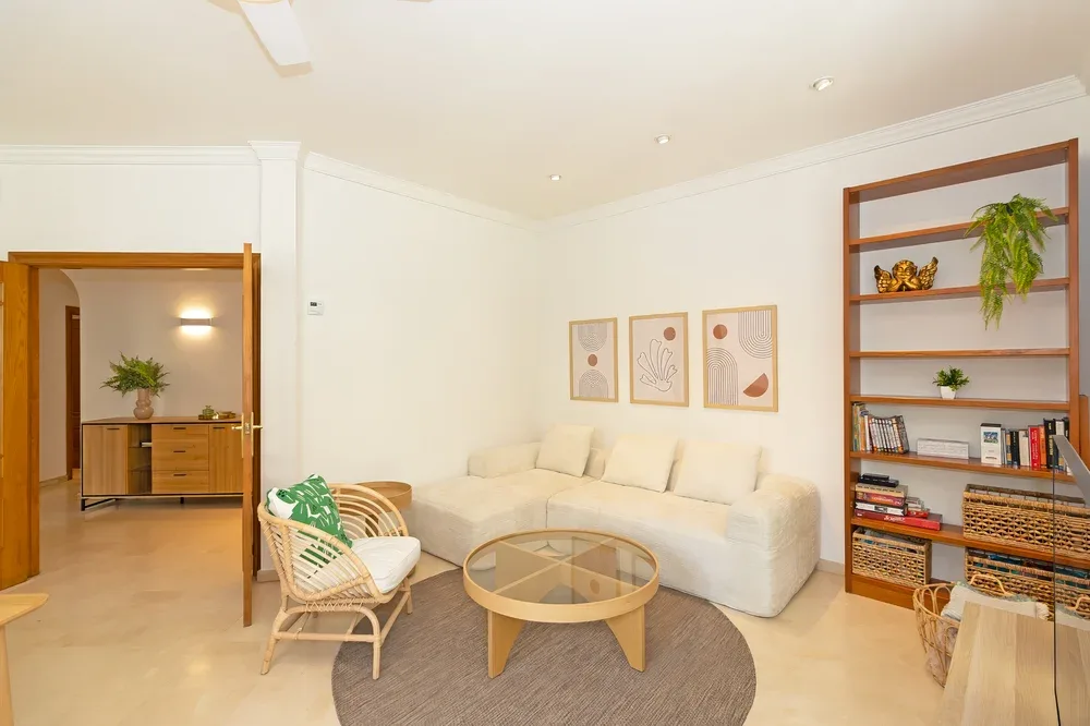 A bright living room with a cream seating area and round coffee table.