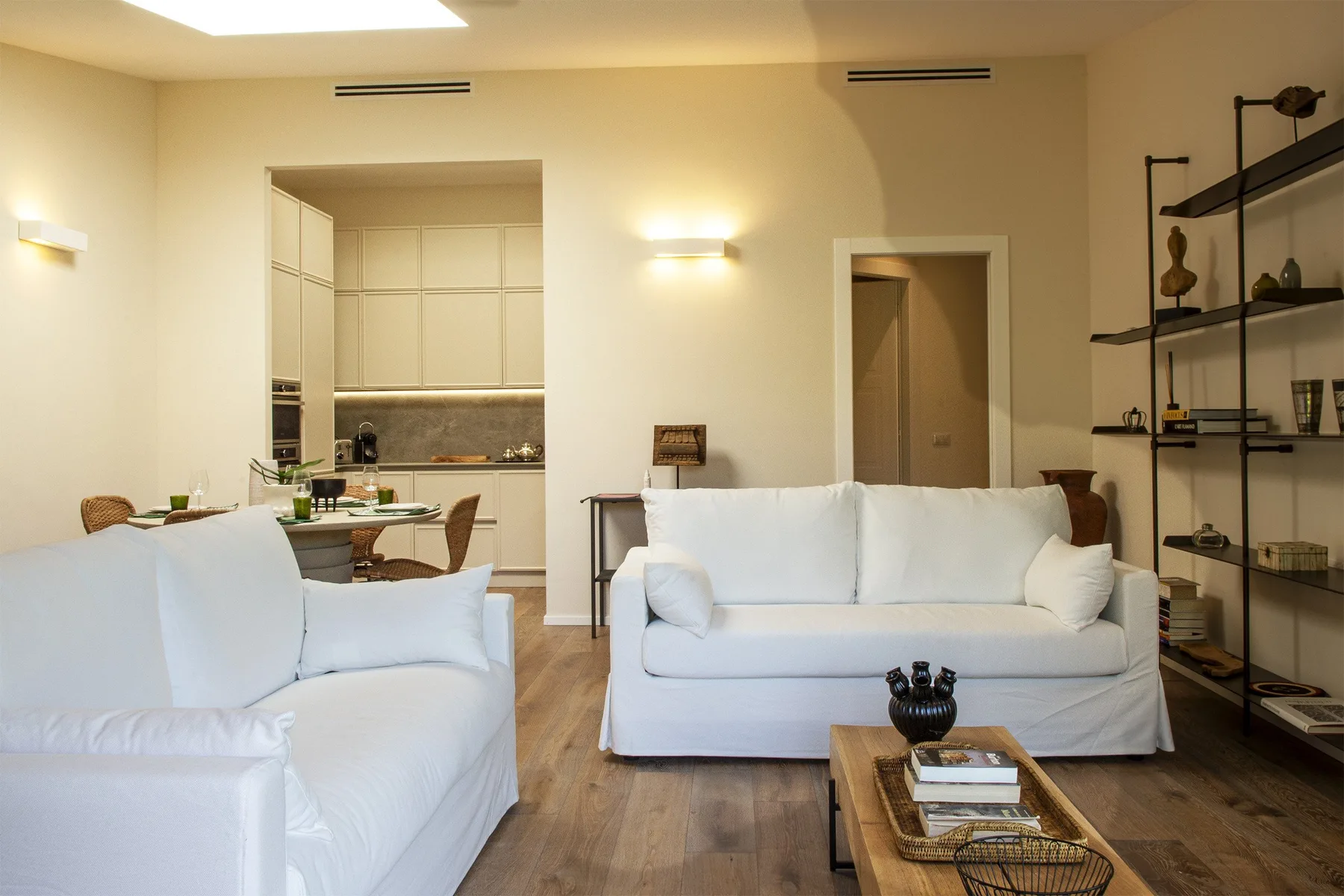 A living room with white seating, a coffee table, and open shelving.