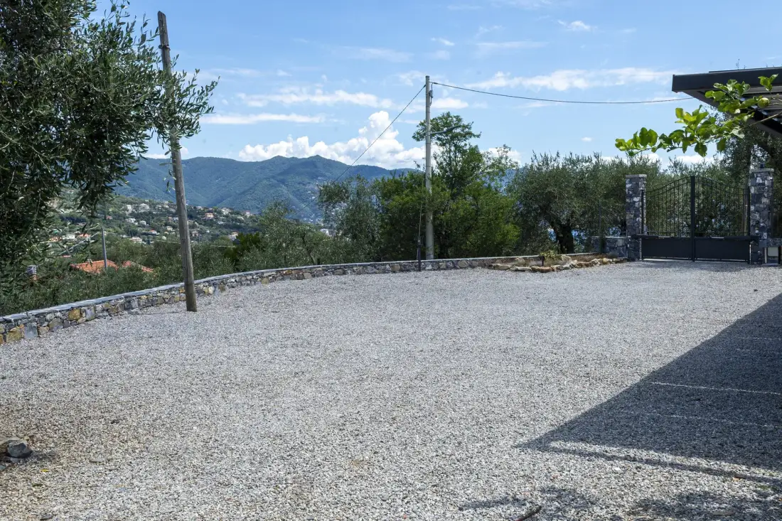 A gravel courtyard overlooks a hillside town and distant mountains.