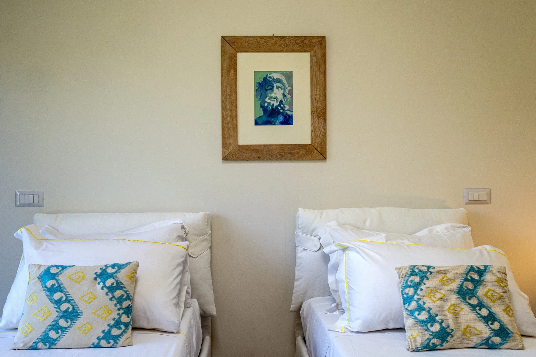 A bedroom with two beds and a framed picture on the wall.