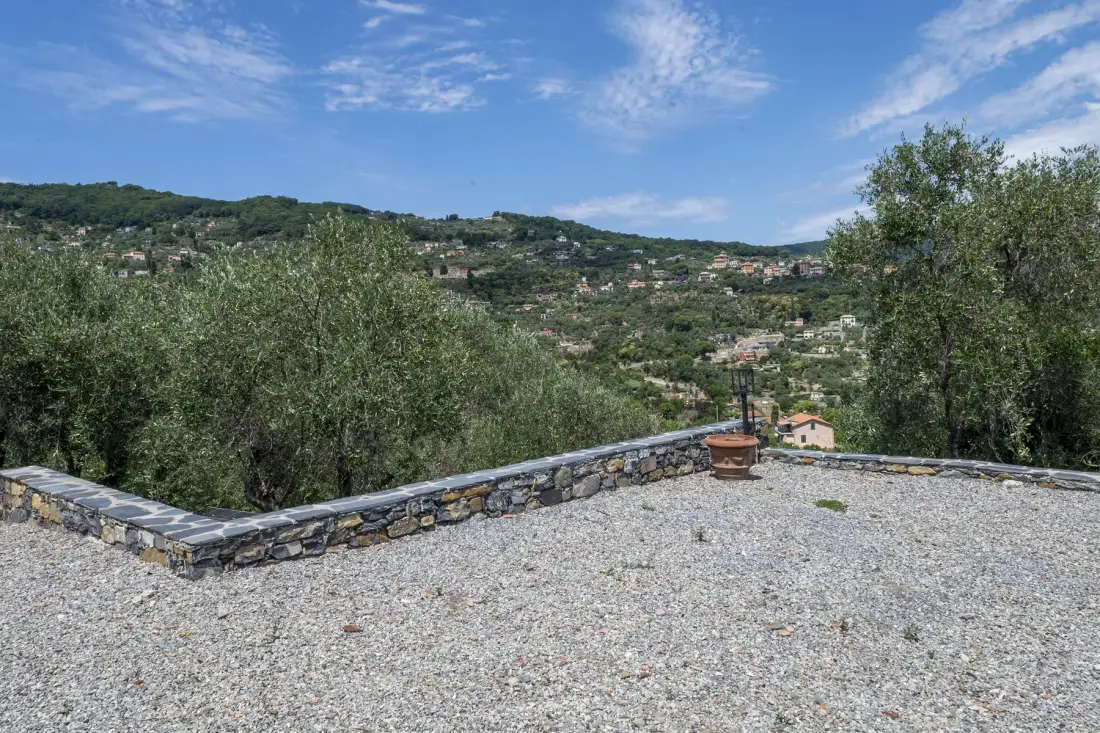 A gravel terrace overlooks a green hillside dotted with houses.